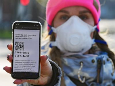 Девушка в медицинской маске демонстрирует на экране мобильного телефона своей цифровой пропуск с QR-кодом на передвижение по территории Москвы. Фото: Игорь Иванко / Коммерсант