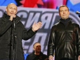 Владимир Путин и Дмитрий Медведев на фоне лозунга 